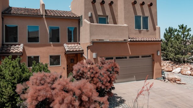 A two-story house with a garage, multiple windows, and a tiled roof. - Beautiful Desert Wind Townhome in Moab with 2 Master Suites. Recently updated! (Moab)
