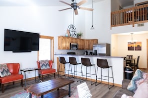 Un espacio habitable moderno con cocina, comedor y una zona de estar con un sofá rojo y una mesa de madera.