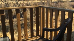 A wooden deck with a chair and a table, overlooking a mountainous landscape with sparse vegetation. - 30 Miles from Yellowstone Park! View is Breathtaking! (Emigrant)