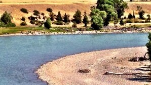 A river with a pebbly bank and trees in the background. - 30 Miles from Yellowstone Park! View is Breathtaking! (Emigrant)