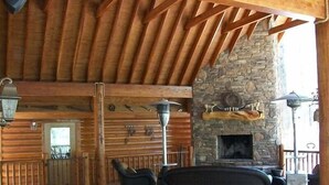 Ein Holzhütten-Interieur mit Kamin aus Stein, Holzbalken und Sitzgelegenheit im Freien.