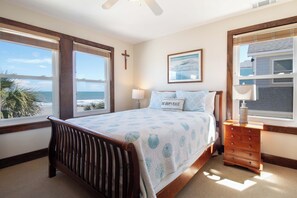 Une chambre à coucher avec un lit, une table de chevet, une lampe, une croix accrochée au mur et un tableau encadré.