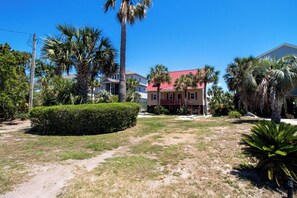A residential area with a red house, palm trees, and a well-maintained lawn.