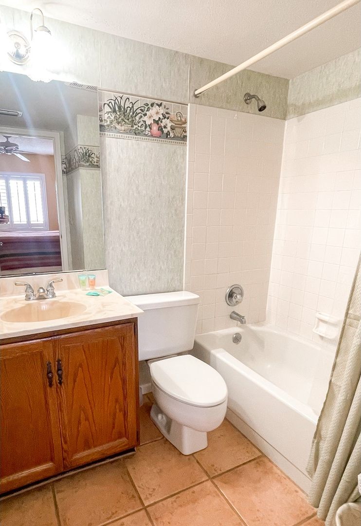 A bathroom with a wooden vanity, a white toilet, a bathtub, and a shower.