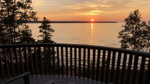 A deck with wooden railings overlooking a calm body of water during sunset. - Huron Horizons - Magical Sunsets & Four Seasons of Recreational Opportunities! (Big Bay)