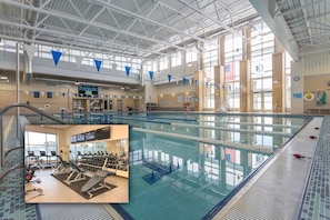 Une piscine intérieure avec des couloirs de nage, un plongeoir et un espace de remise en forme équipé de matériel d’exercice.