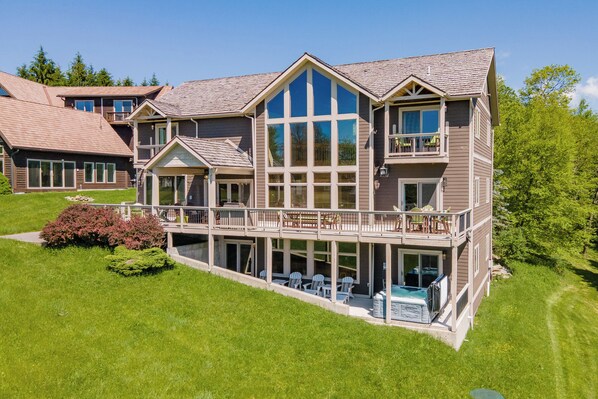 A large two-story house with a balcony, a swimming pool, and a well-maintained lawn.