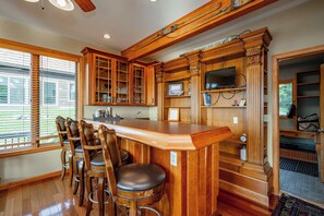 Una cocina con armarios de madera, una zona de bar con taburetes y vistas por la ventana.