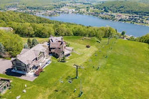 Un grand bâtiment à étages, un télésiège et un lac en arrière-plan.