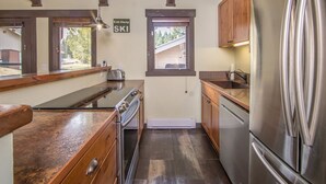 Una cocina compacta con armarios de madera, un refrigerador de acero inoxidable y una ventana sobre el fregadero.