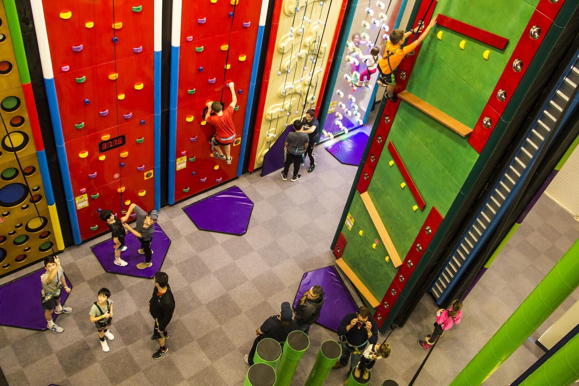 Instalación de escalada en interiores con varias paredes de escalada y colchonetas acolchadas en el suelo.