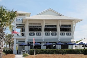 A two-story building with a flat roof, large windows, and a covered outdoor seating area with umbrellas. - Gulf Front - Beach Chairs* Endless Views (Santa Rosa Beach)