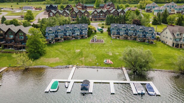 Ett hotell vid sjön med flera byggnader, en brygga med båtar och en lekplats.