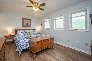 Een slaapkamer met een houten bed, een plafondventilator en uitzicht op de omgeving.