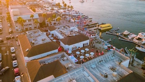 Vista aérea de un puerto deportivo con barcos amarrados, un aparcamiento y un edificio con terraza.