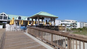 A pier with outdoor seating and umbrellas, a sign reading "Pier 101", and buildings in the background.