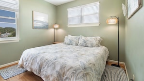 A bedroom with a bed, two bedside lamps, a window, and a wall-mounted picture. - Oceanfront 1Br/1Ba Condo~Little Peace of Heaven (Folly Beach)