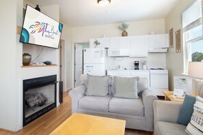 Ein Wohnzimmer mit einer Couch, einem Couchtisch, einem Kamin und einem an der Wand befestigten Fernseher.