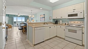 A modern kitchen with white cabinets, a central island, and a view to the outside. - 3rd Floor, Private Oceanfront Balcony, AshWorth, Sleeps 8 | Ashworth - 308 (North Myrtle Beach)