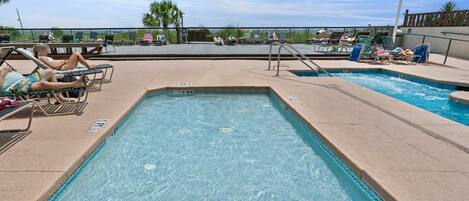A pool area with multiple lounge chairs and a sign indicating a depth of 1 FT.