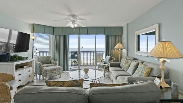 A living room with a television, sofa, chairs, and a balcony with a view. - 3rd Floor, Private Oceanfront Balcony, AshWorth, Sleeps 8 | Ashworth - 308 (North Myrtle Beach)