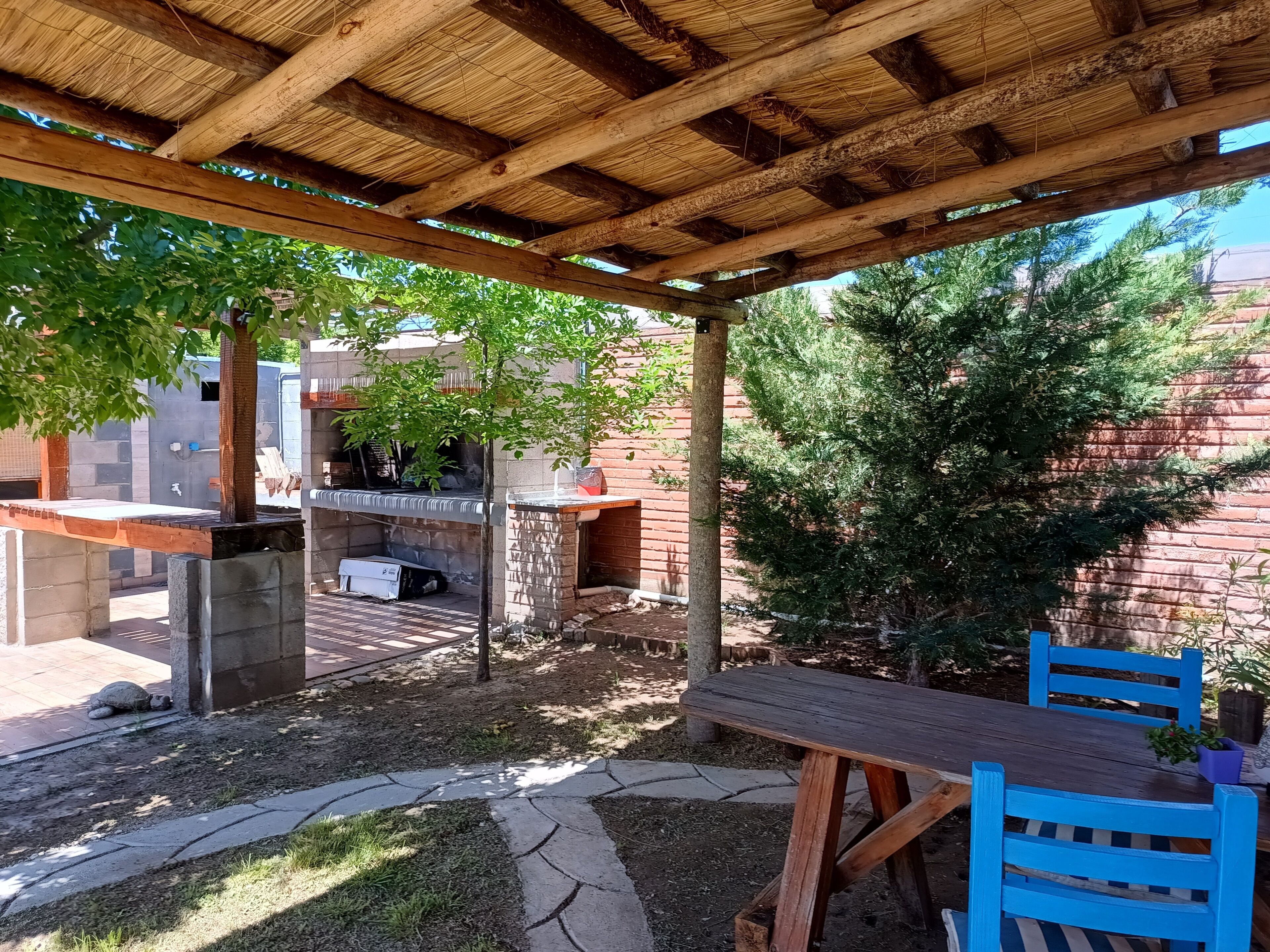 A covered outdoor area with a barbecue grill, a table, and chairs.