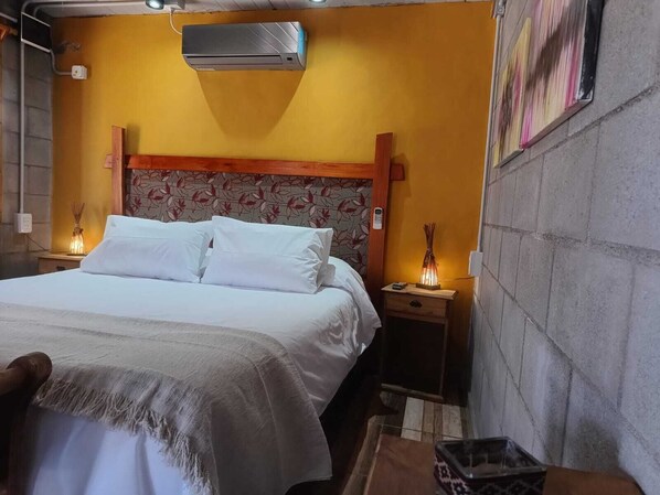 Ein Hotelzimmer mit einem Bett, Nachttischlampen, einer Klimaanlage und einem Wandbild.
