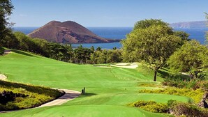 Un parcours de golf offrant une vue sur l’océan et sur une montagne en arrière-plan.