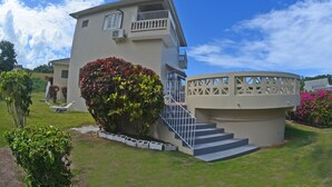 A two-story building with a balcony, a circular structure with steps, and a well-maintained lawn.