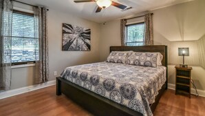 Ein Schlafzimmer mit Bett, Deckenventilator, Nachttisch und Lampe.
