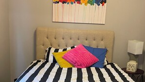 A bed with a striped black and white bedspread, a tufted headboard, and colorful pillows.
