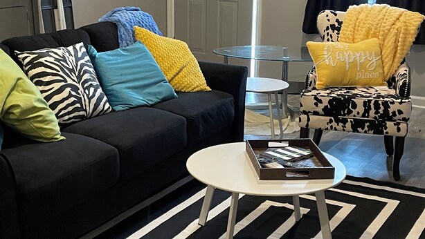 A living room with a black sofa, a round coffee table, and a patterned rug.
