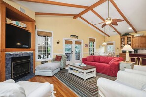 TV, fireplace, DVD player, books - Woodlands Wonder: Cute Oak Island Cottage with Private Pool Welcomes Nightly Res (Oak Island)