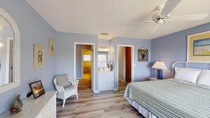 A bedroom with a bed, a nightstand, a chair, a dresser, and a ceiling fan.