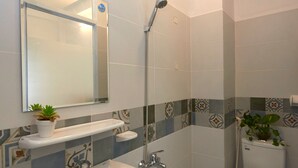 Une salle de bain équipée d’un lavabo, d’un miroir, de toilettes et d’une douche.