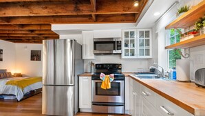 A modern kitchen with stainless steel appliances, white cabinetry, and a wooden ceiling. - Tiny House in Alameda/Alberta Arts ~ Dog Friendly (Portland)