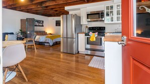 A modern kitchen with stainless steel appliances, a wooden ceiling, and a dining area with a white table and chairs. - Tiny House in Alameda/Alberta Arts ~ Dog Friendly (Portland)