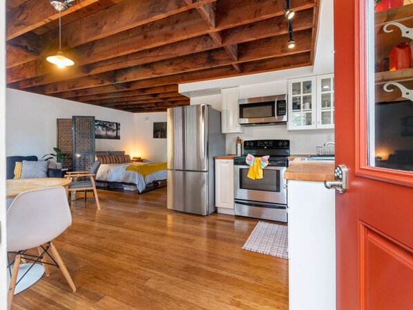 A modern kitchen with stainless steel appliances, a wooden ceiling, and a dining area with a white table and chairs.