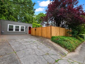 A residential property with a garage, a red door, and a wooden fence.