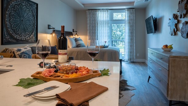 Una habitación bien iluminada con una mesa de comedor dispuesta para una comida, una cama con vistas y un ventilador de techo.