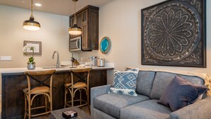 Una cocina moderna con armarios de madera oscura, una zona de bar con taburetes y una gran pieza decorativa de metal en la pared.
