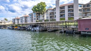Un port de plaisance avec des bateaux amarrés, une rampe d’accès aux bateaux abritée et, au fond, des immeubles résidentiels à plusieurs étages.
