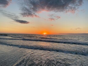 A sunset over a beach with waves.