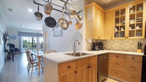 A modern kitchen with wooden cabinets, a stainless steel sink, and hanging pots. - Spacious Condo Close to Everything! -Pier Pleasure (Folly Beach)