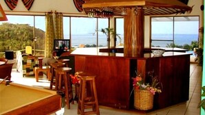 Une pièce spacieuse équipée d’une table de billard, d’un coin bar et de grandes fenêtres offrant une vue sur l’océan.