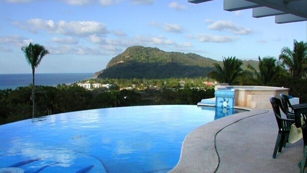 Une piscine avec vue sur la montagne et l’océan.