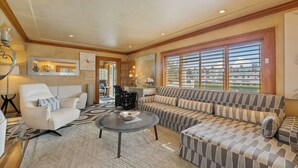 A spacious living room with a large sofa, a coffee table, and a patterned rug.