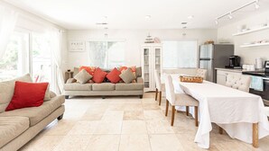 Una sala luminosa con un sofá, una mesa de comedor y una zona de cocina.