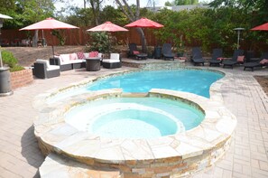 Un patio trasero con piscina, bañera de hidromasaje y mobiliario exterior.
