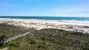 A beach with a wooden boardwalk leading to the shore, sandy dunes, and the ocean. - Ocean Villas 108: Top floor 3 bedroom condo in gated complex - 2 pools, beach (St. Augustine Beach)
